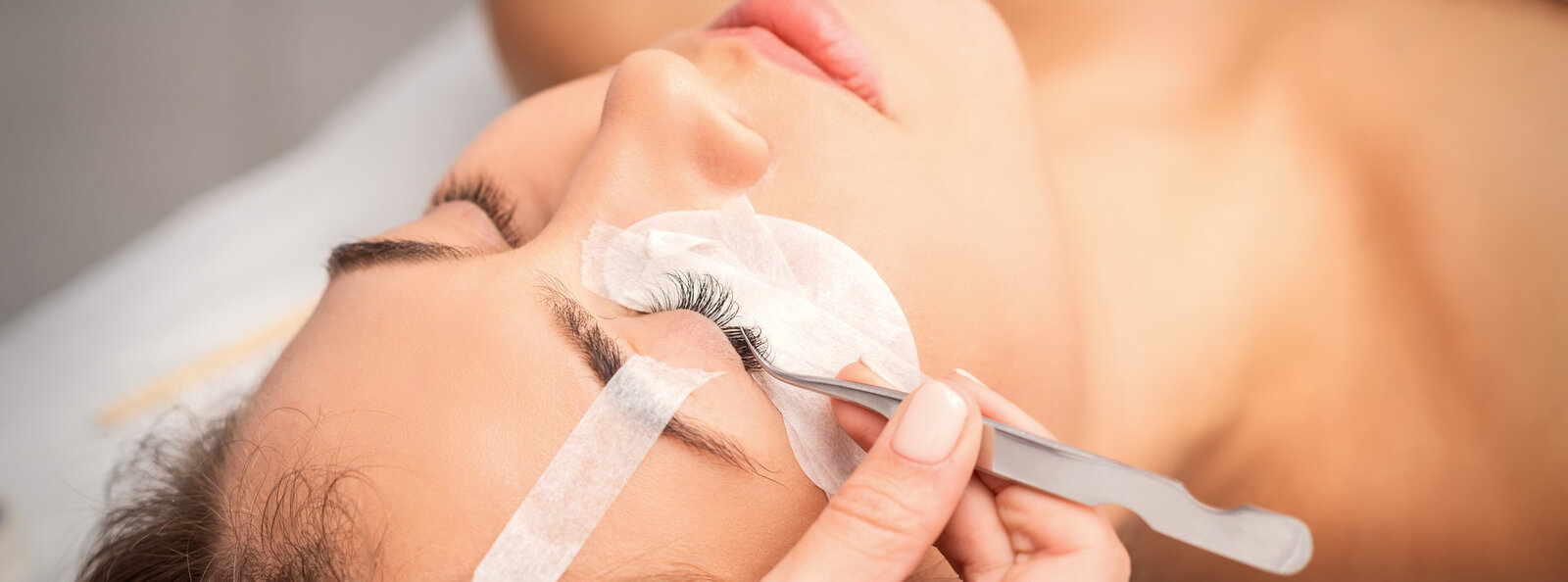 young-caucasian-woman-having-eyelash-extension-procedure-beauty-salon-beautician-glues-eyelashes-with-tweezers.jpg